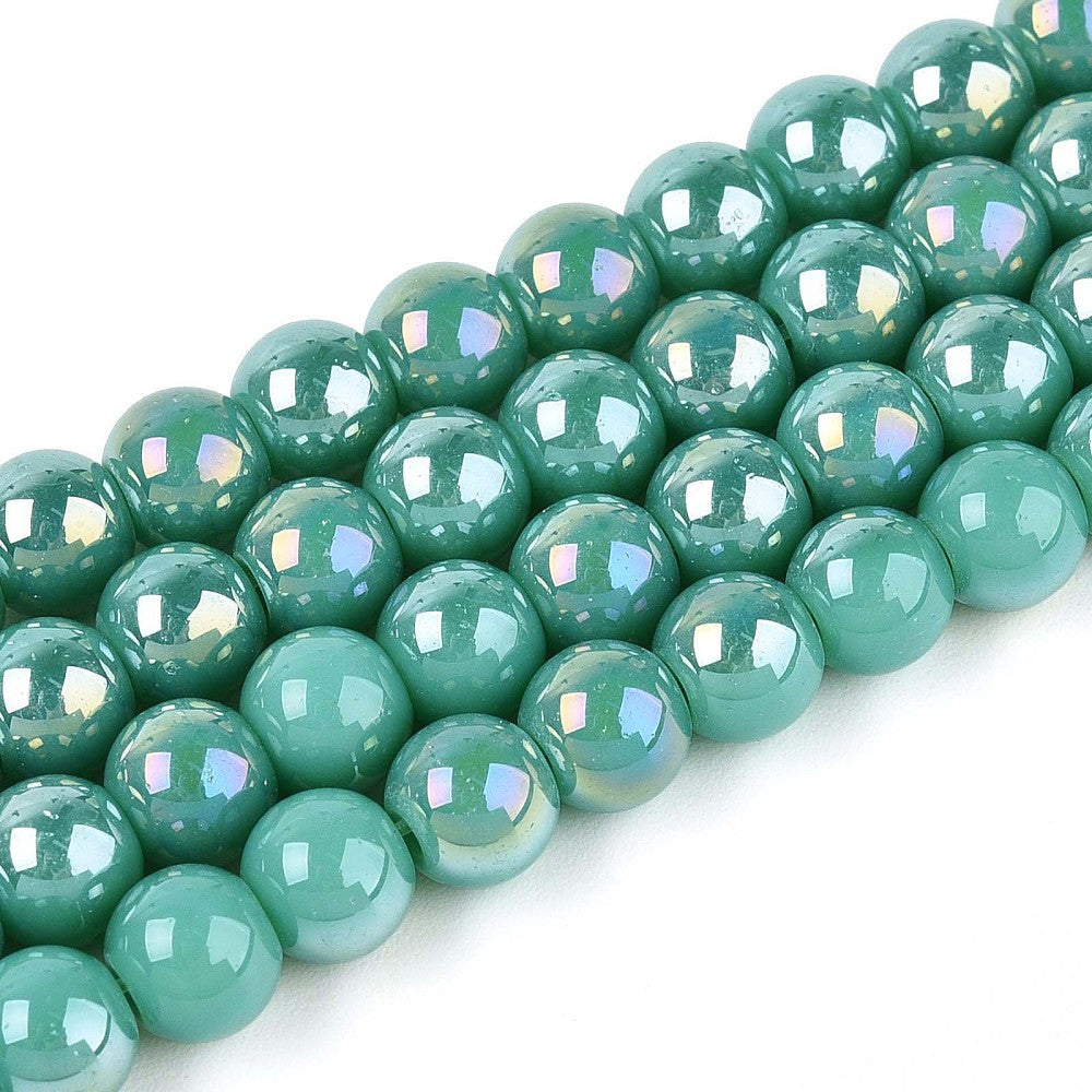 zoomed in sections of four iridescent turquoise green glass bead strands over white surface.  