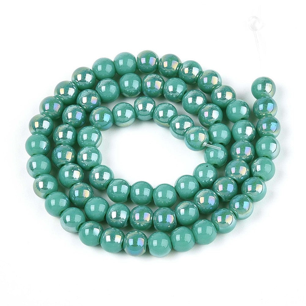 iridescent turquoise green glass bead strand in swirl design over white surface.  