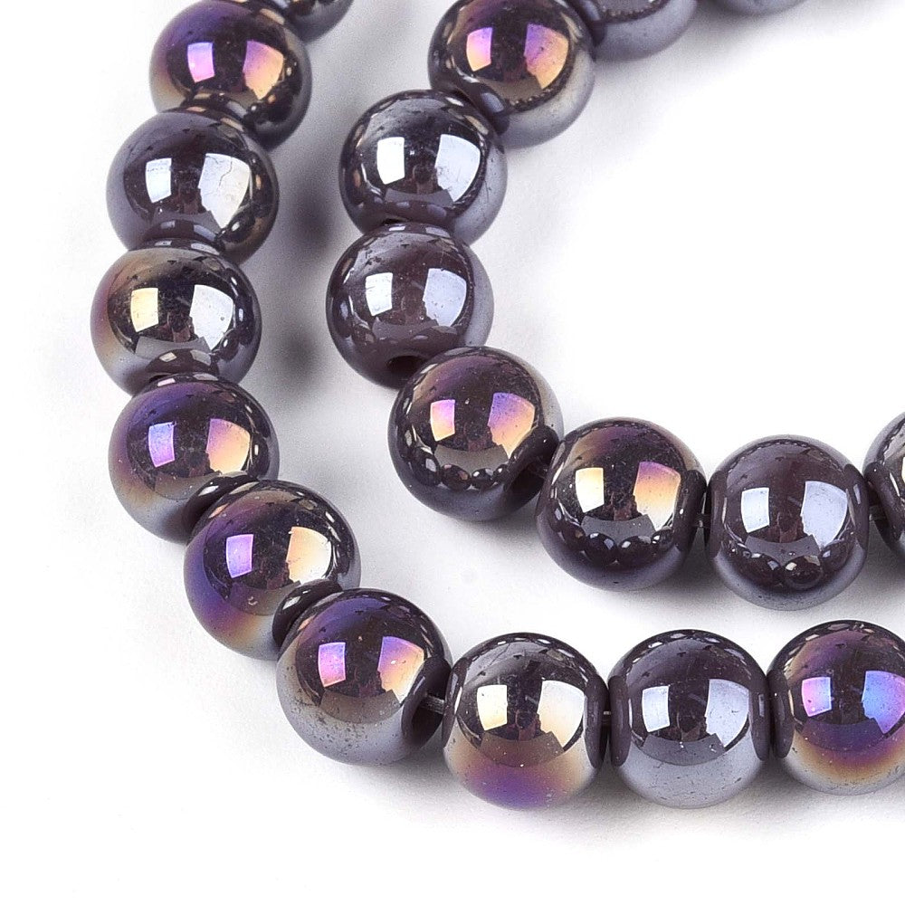 zoomed in sections of iridescent  lavender glass bead strand over white surface.  