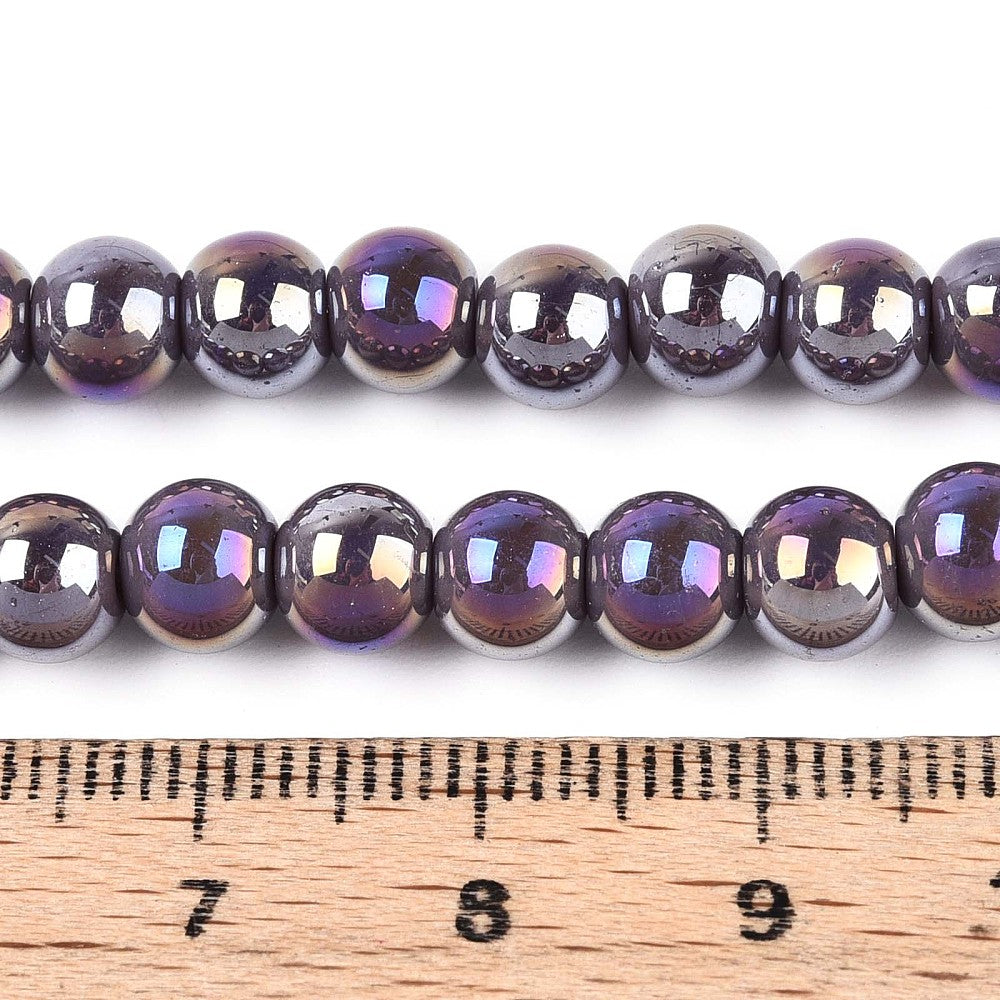 iridescent lavender glass bead strand displayed above wooden ruler with white background. 