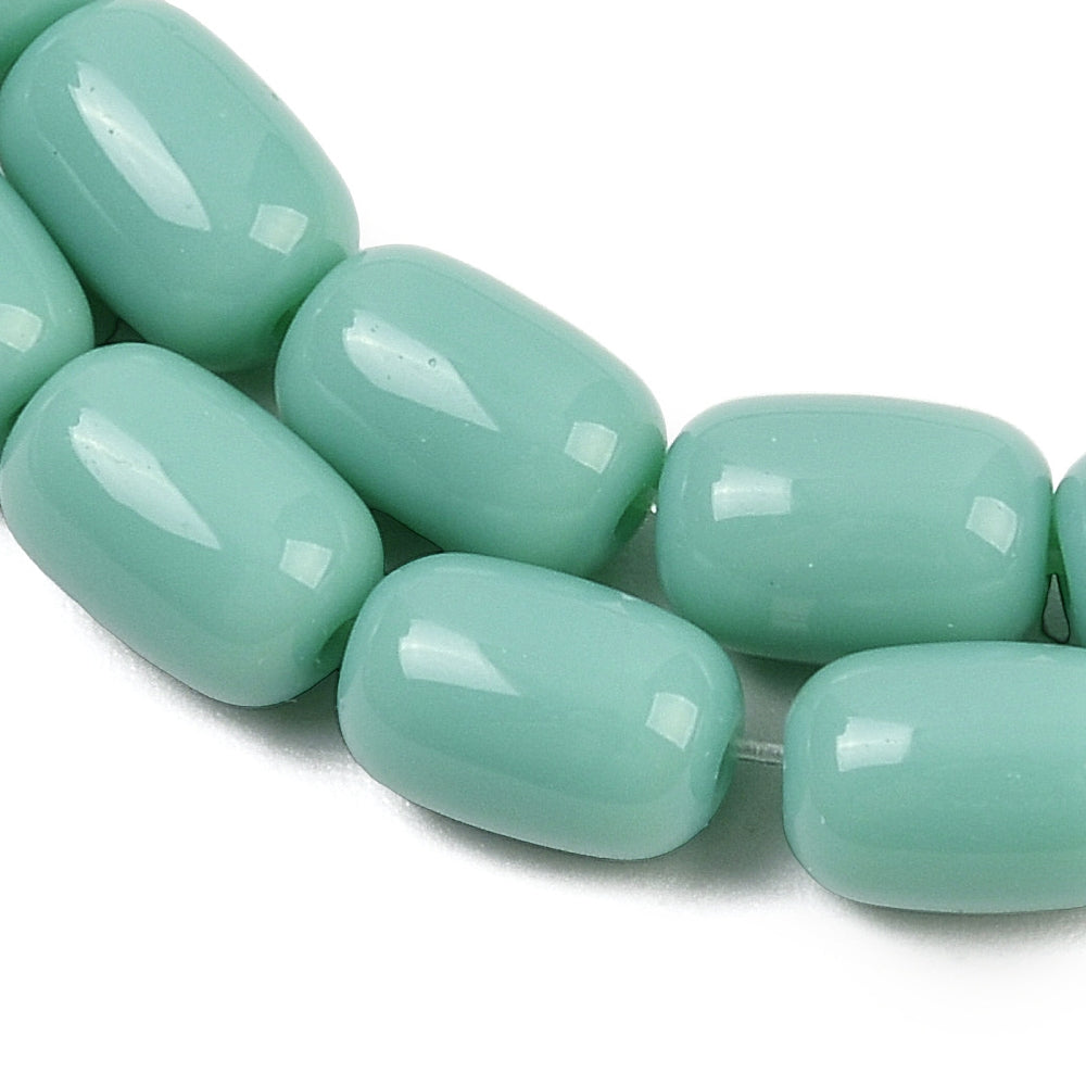 zoomed in sections of turquoise green barrel bead strands over white surface.