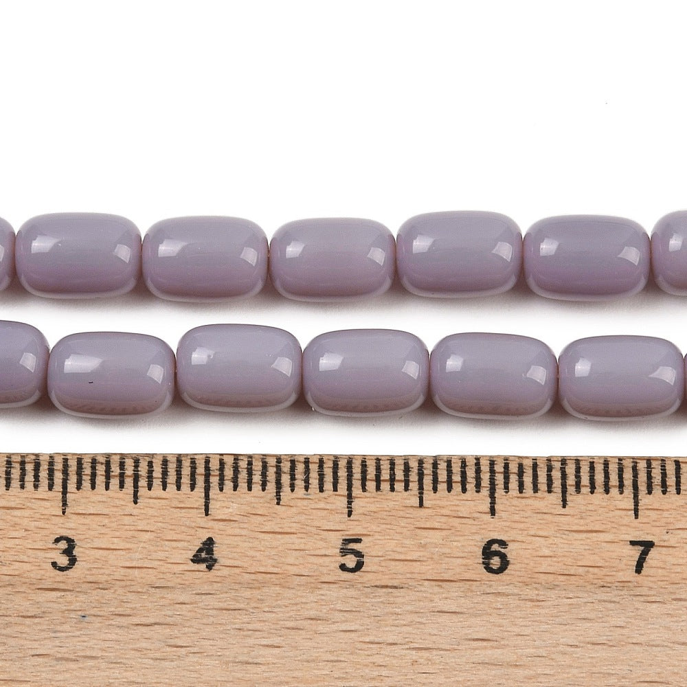 zoomed in sections of lavender barrel bead strands above wooden ruler over white surface.