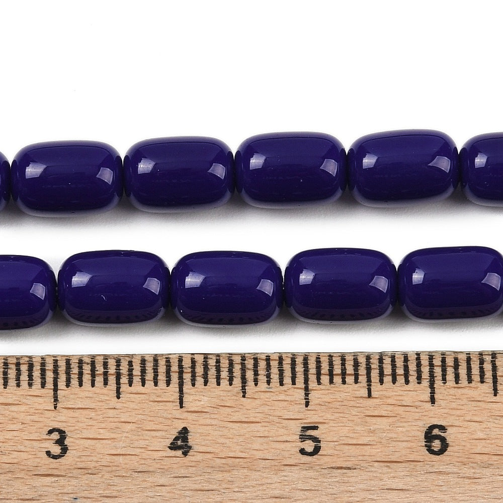 zoomed in sections of dark blue barrel bead strands above wooden ruler over white surface.