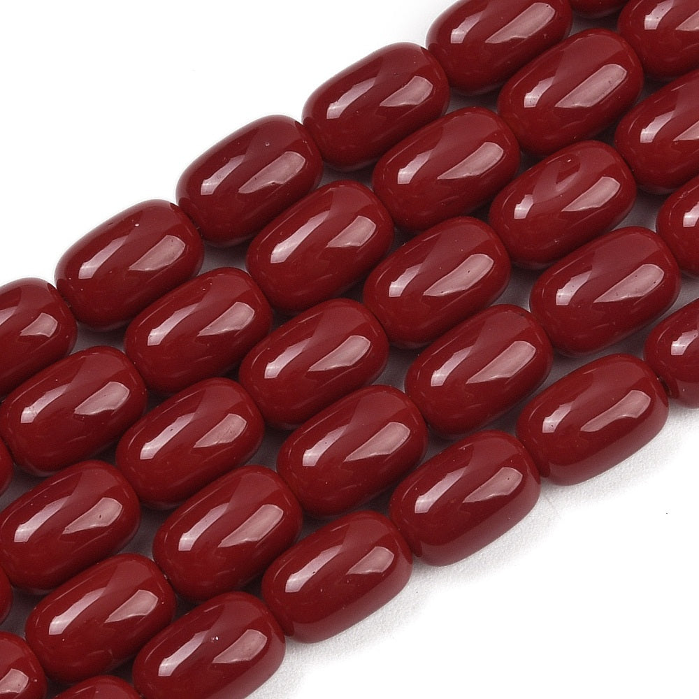 zoomed in sections of red barrel bead strands over white surface.