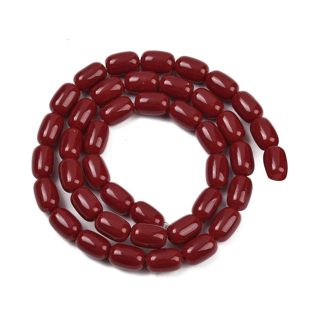 red glass barrel bead strand in swirl design over white surface. 