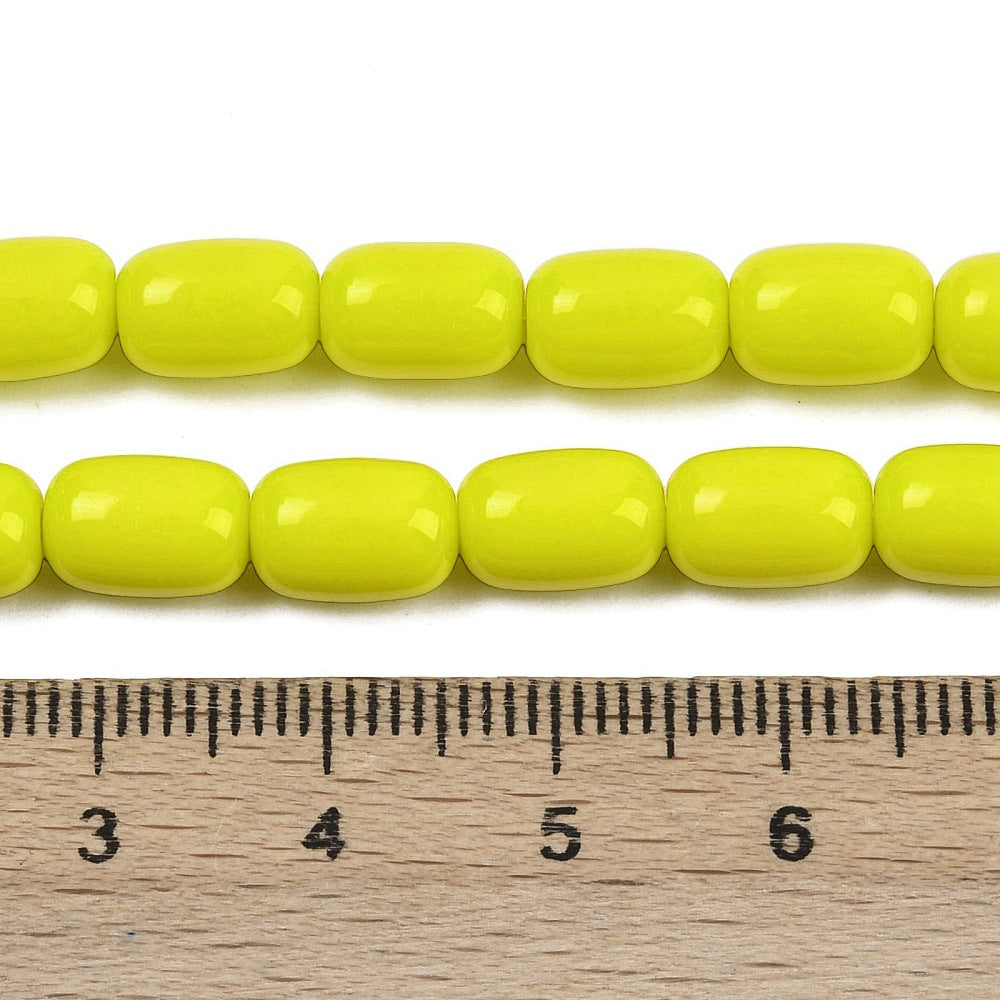 zoomed in sections of yellow barrel bead strands above wooden ruler over white surface.