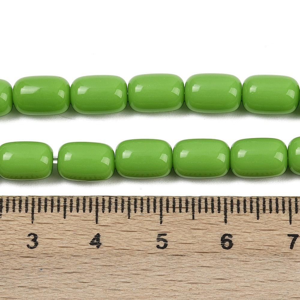 zoomed in sections of lime green barrel bead strands above wooden ruler over white surface.