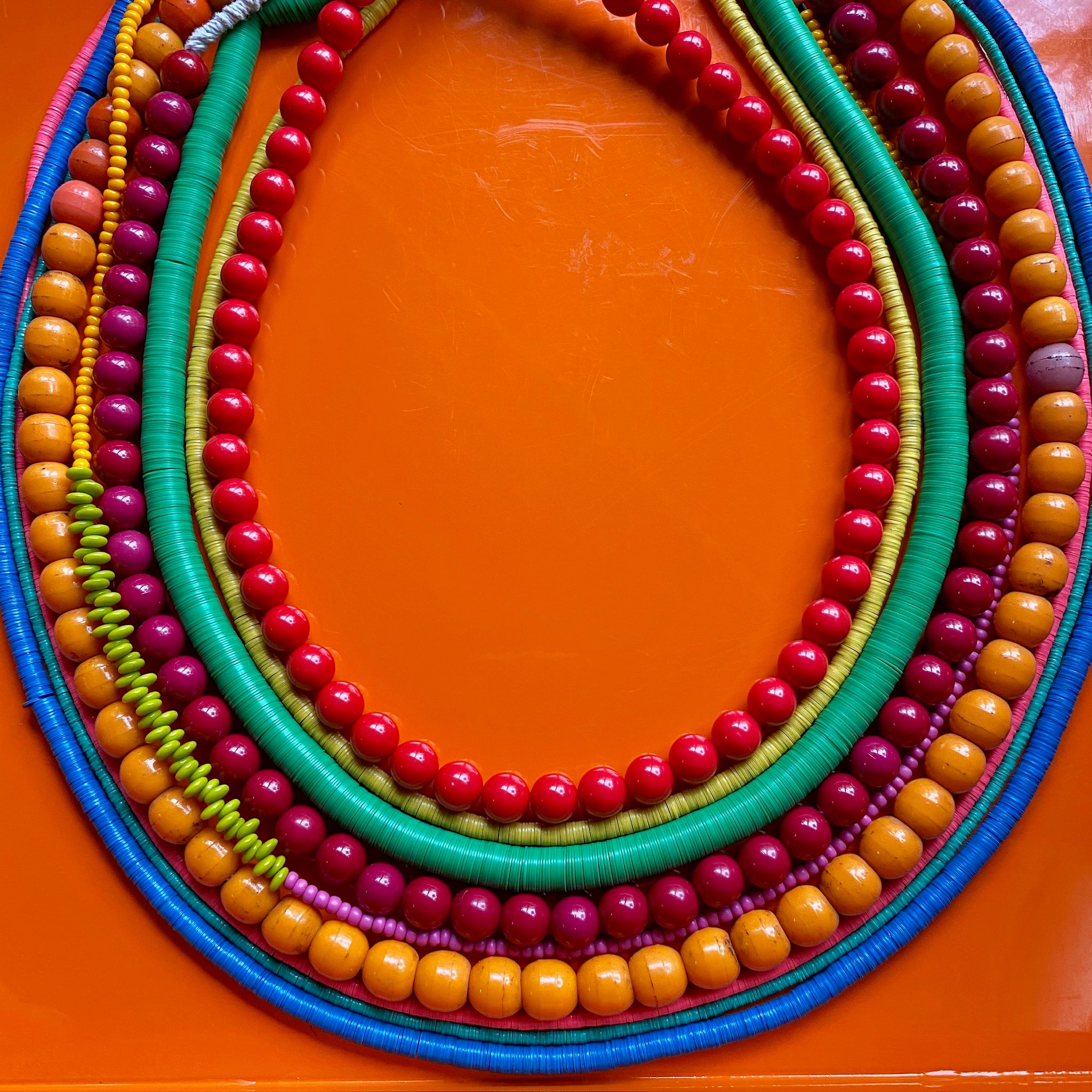 Colorful beaded necklaces on an orange background