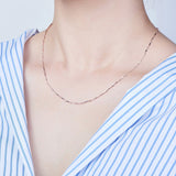 silver pinched bar link chain necklace displayed on neck with blue and white striped shirt with white background. 