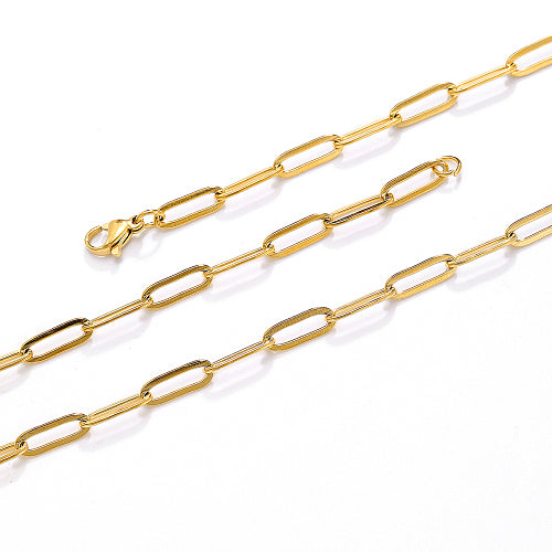 zoomed in sections of golden flat paperclip chain necklace with lobster claw clasp over white background. 