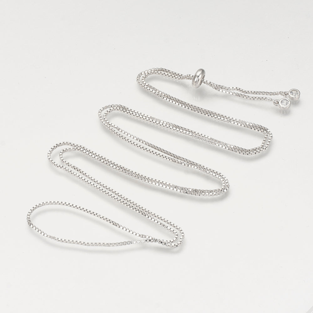 silver tone Bolo box chain slider necklace with slider bead and bezel set clear stone stopper beads on white background. 