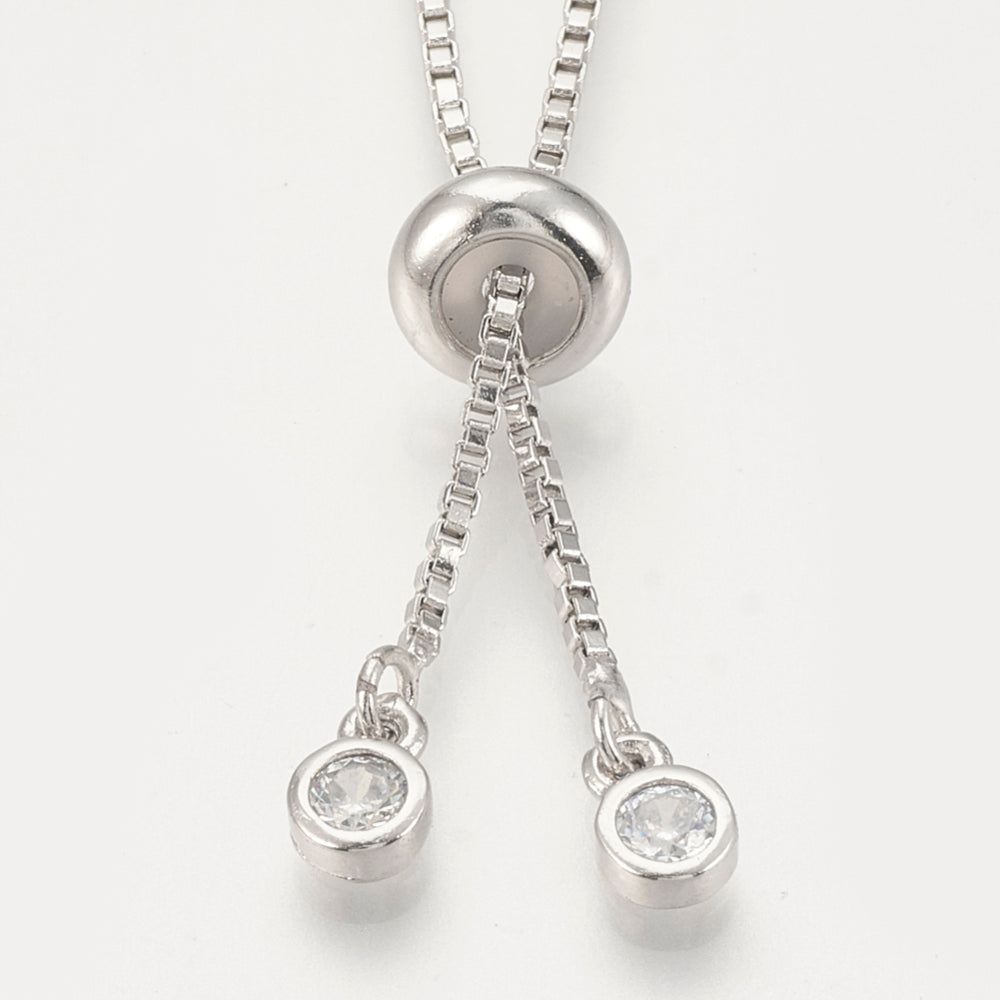 zoomed in silver tone slider bead and bezel set clear stone stopper beads on box chain Bolo necklace against white background. 