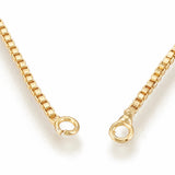 zoomed in section of golden jump ring connectors on adjustable box chain slider necklace over white background. 