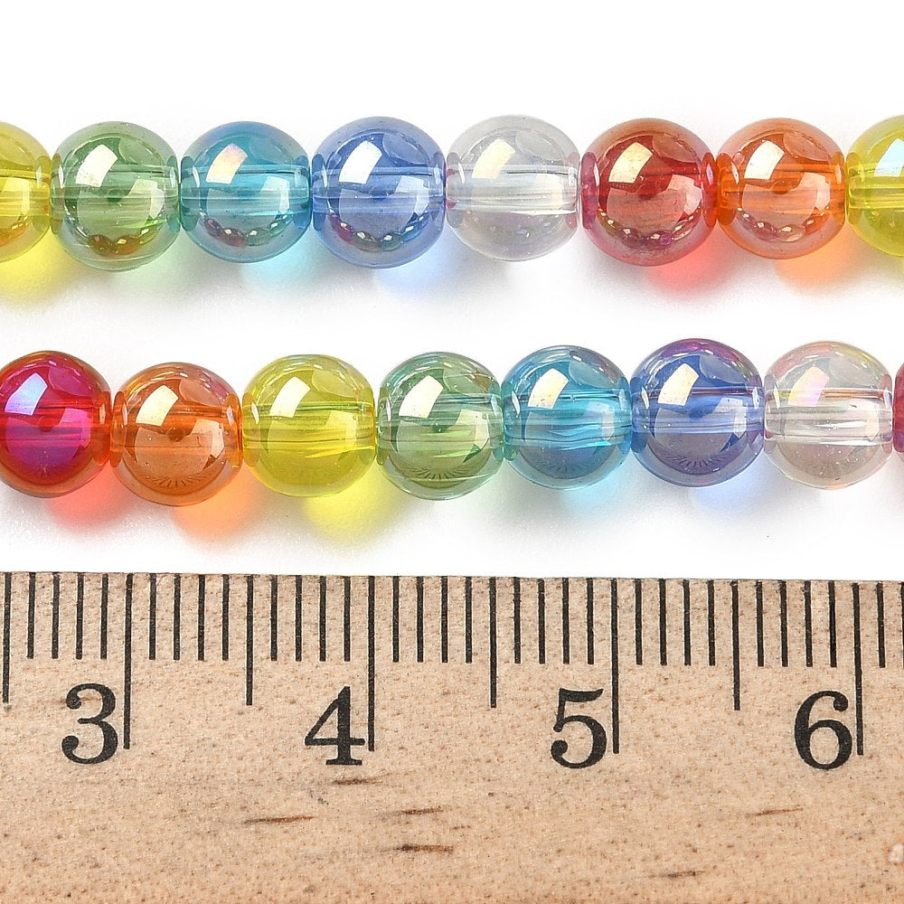 zoomed in sections of iridescent transparent rainbow glass bead strand above wooden ruler over white surface. 