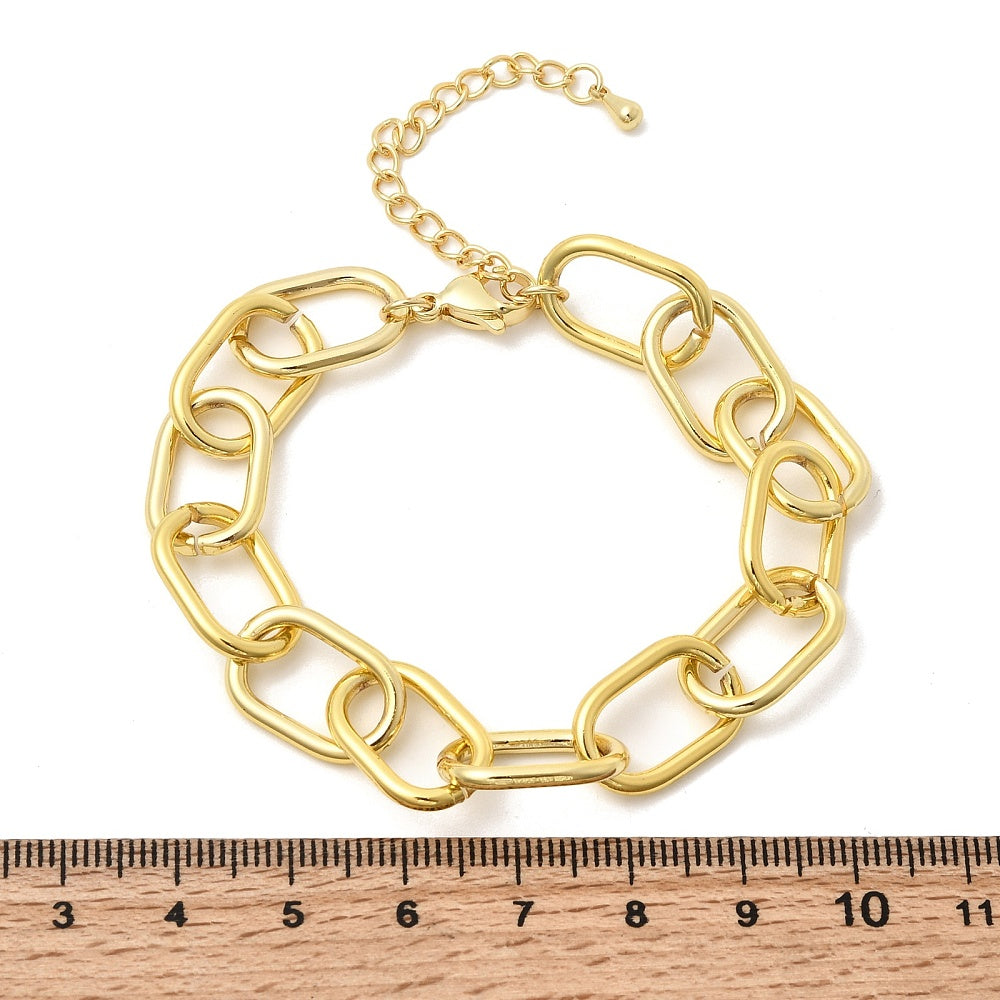 golden large oval cable link chain bracelets with lobster claw clasp and extender chain above wooden ruler over white background. 