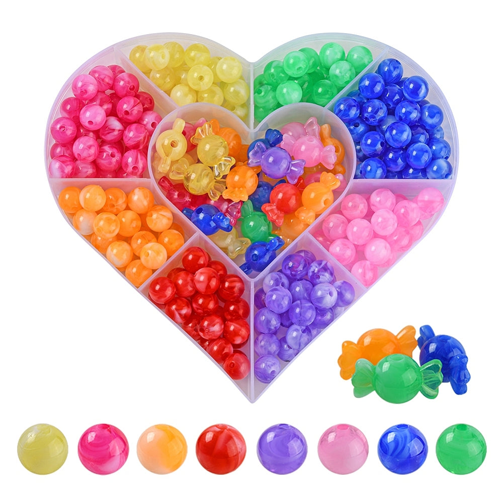 heart shaped plastic bead box divided into nine sections containing large hole round beads in green, blue, pink, purple, red, orange, magenta and yellow and the center section filled with multi-colored candy shaped beads. there are also examples of the loose beads below the box over a white background. 