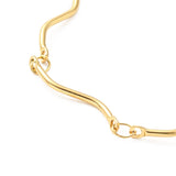 zoomed in section of golden wave bar link chain necklace over white surface. 