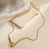 golden snake chain necklace with large hook focal clasp draped over cream colored surface. 