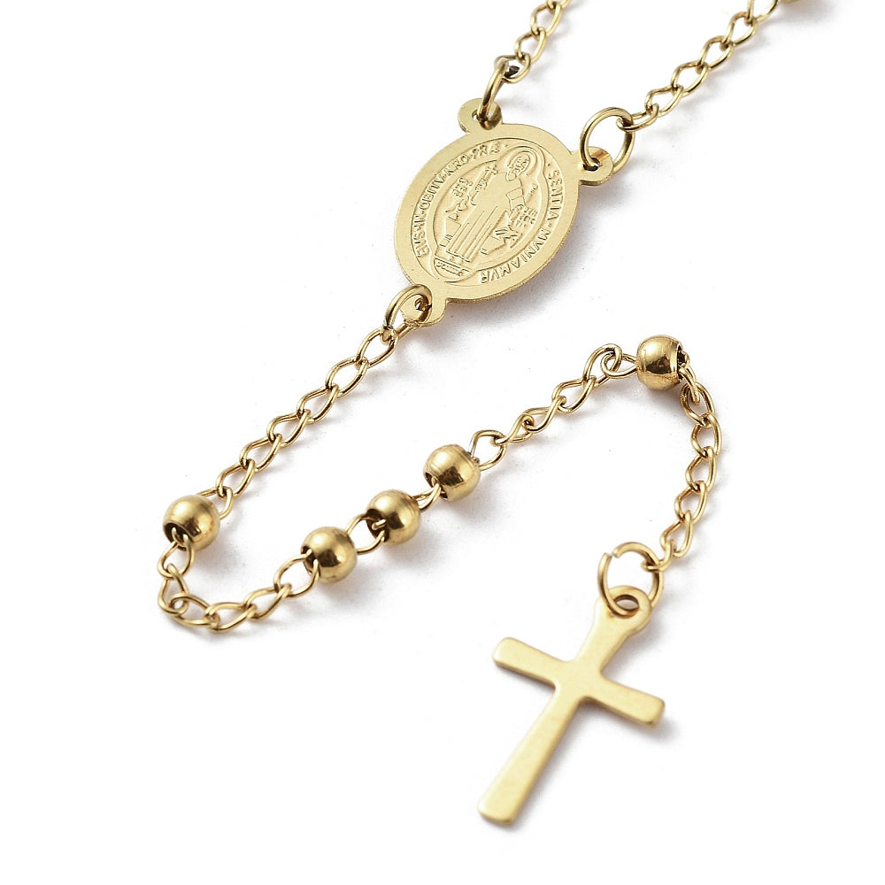 zoomed in front section of golden medal and cross from rosary necklace over white background. 