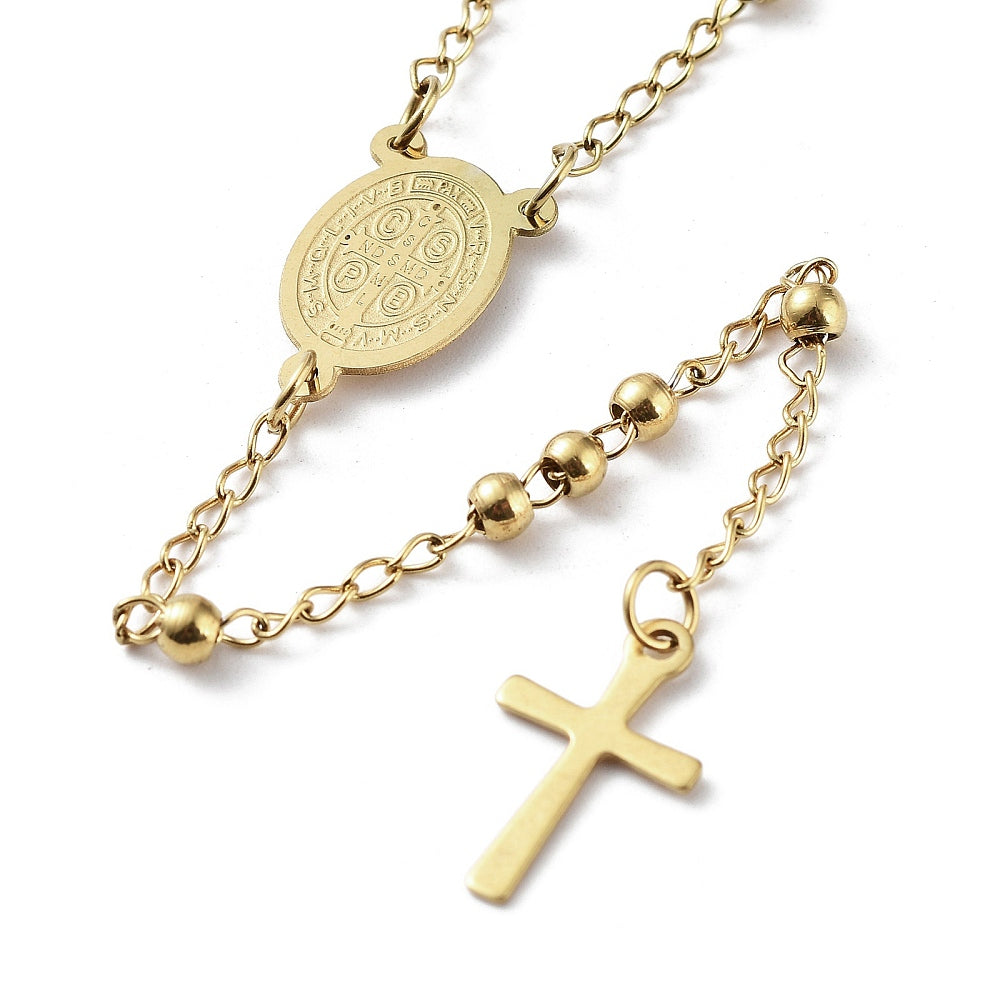 zoomed in back section of golden medal and cross from rosary necklace over white background. 