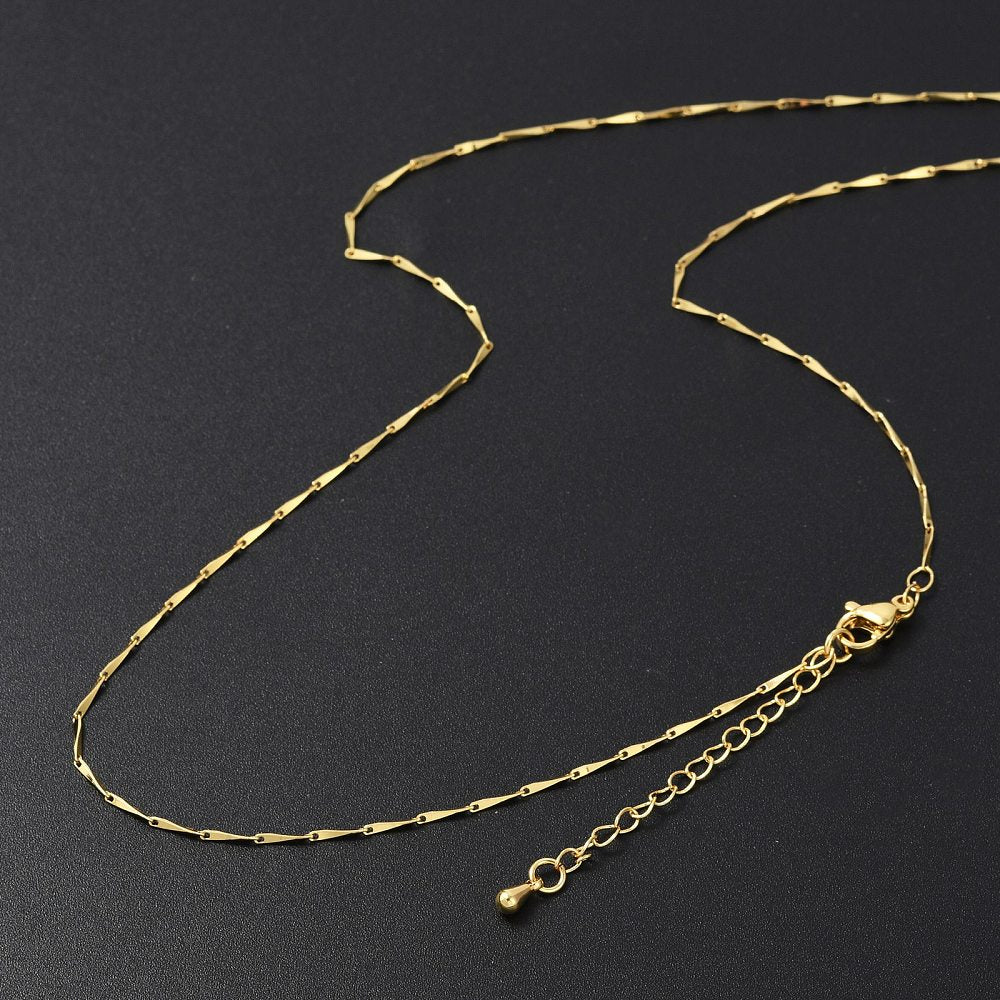 golden twisted bar link necklace with lobster claw clasp and extender chain on black background.