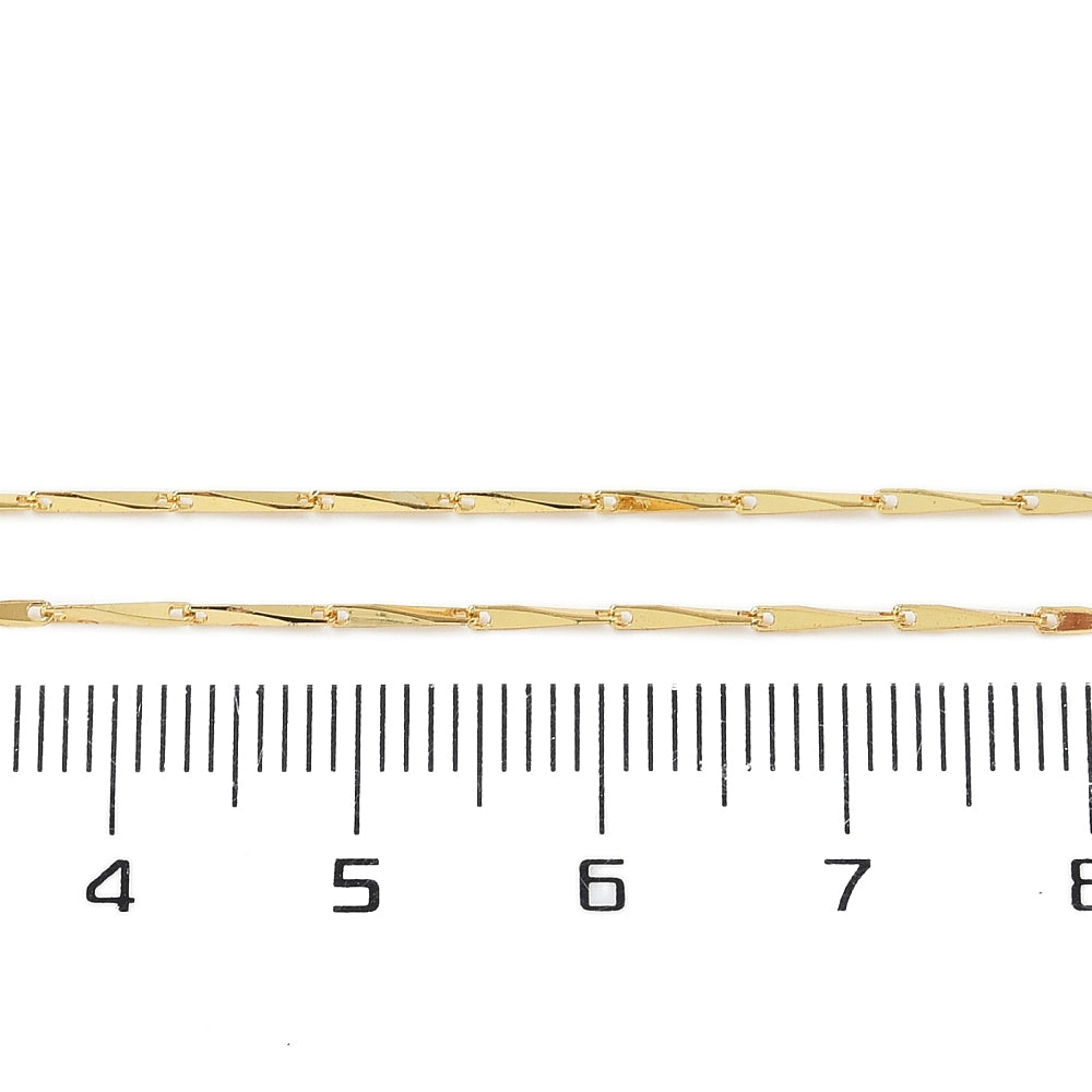 golden twisted link chain displayed over ruler on white background. 
