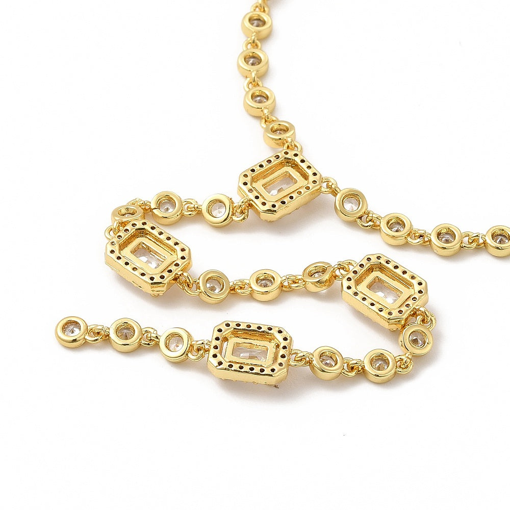 zoomed in back section of golden clear rectangle and round stone link lariat Y necklace over white surface. 