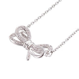 zoomed in front of silver tone bow pendant necklace with clear round stones on a cable chain over white background. 