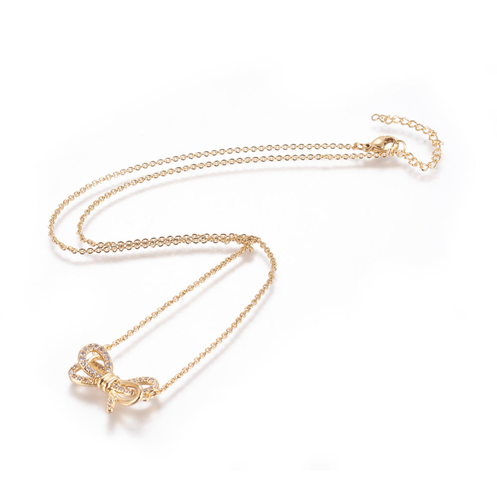 golden bow pendant necklace with clear round stones on a cable chain with lobster claw clasp and extender chain over white background. 