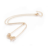 golden bow pendant necklace with clear round stones on a cable chain with lobster claw clasp and extender chain over white background. 