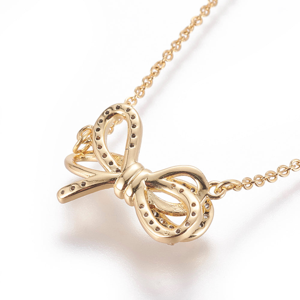 zoomed in back of golden bow pendant necklace with clear round stones on a cable chain over white background. 