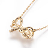 zoomed in back of golden bow pendant necklace with clear round stones on a cable chain over white background. 