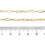 zoomed in sections of golden paperclip chain necklace displayed above ruler over white surface. 