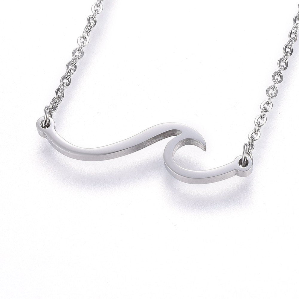 silver tone wave pendant necklace on cable chain over white surface. 