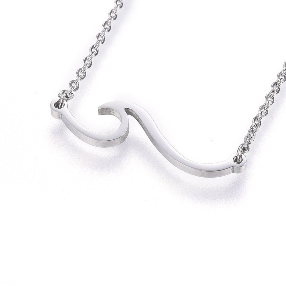 silver tone wave pendant necklace on cable chain over white surface. 
