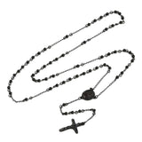 black rosary bead necklace with oval medal connector and crucifix pendant over white background. 