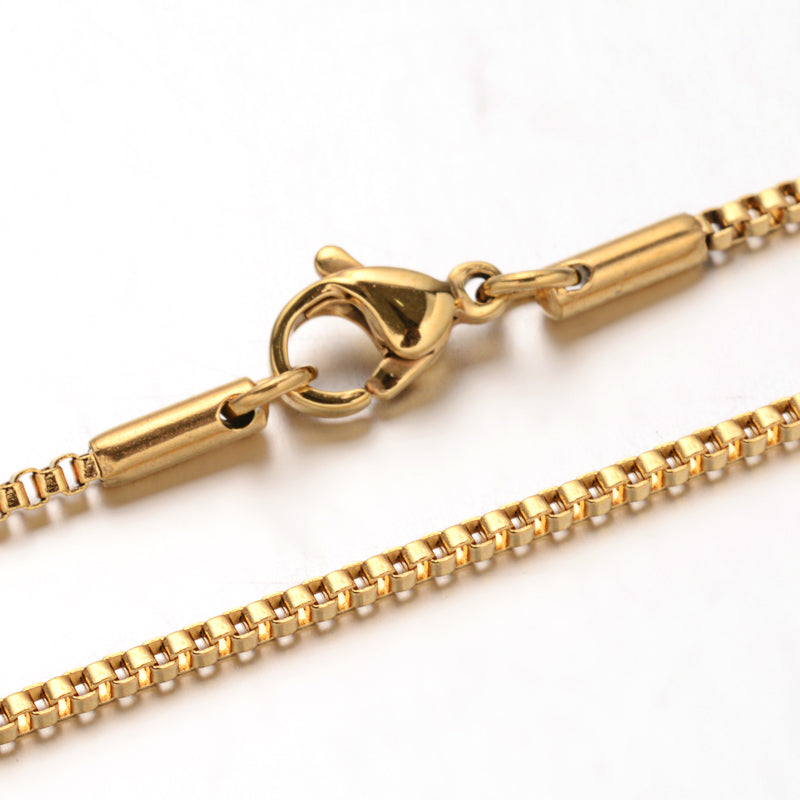 zoomed in sections of golden box chain necklace with lobster claw clasp over white background. 