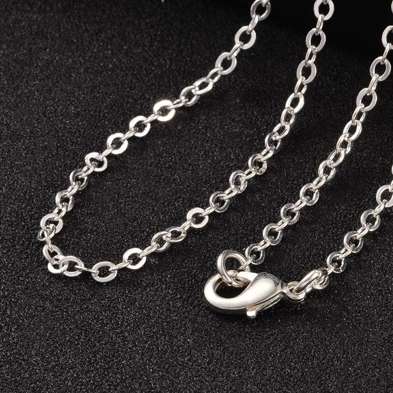silver tone cable chain over black textured surface. 