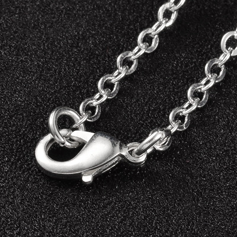 zoomed in section of silver tone cable chain over black textured surface. 