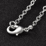 zoomed in section of silver tone cable chain over black textured surface. 