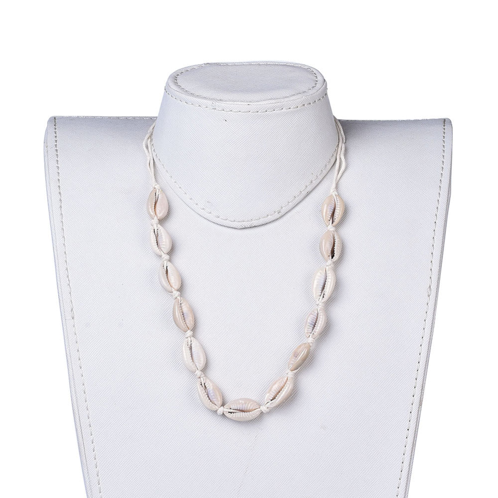 adjustable cowrie choker on white cord displayed at maximum length on white neck from with white background. 
