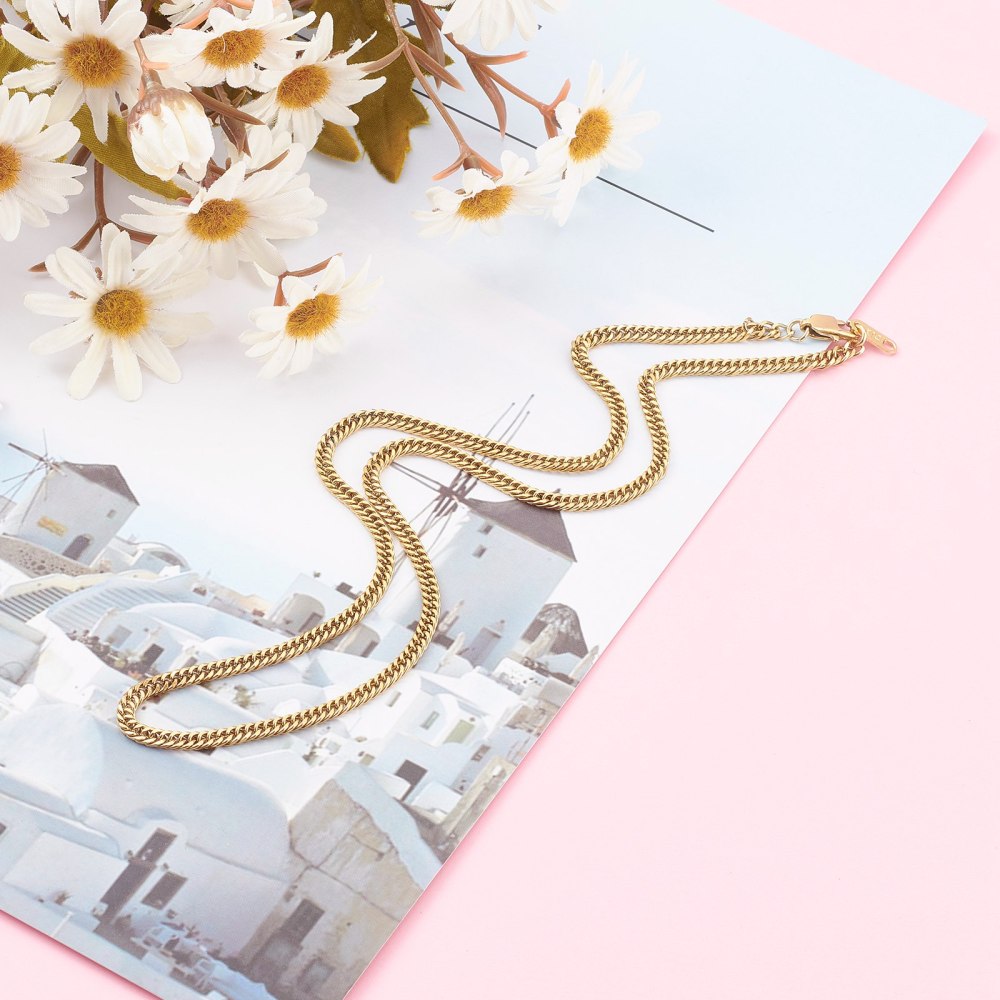 golden small curb chain with lobster claw clasp over photo of Greece on pink surface with daisy flowers in the corner. 
