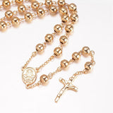 zoomed in front of golden large bead rosary necklace with oval medal connector and crucifix pendant over white background.  