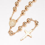 zoomed in back of golden large bead rosary necklace with oval medal connector and crucifix pendant over white background.  