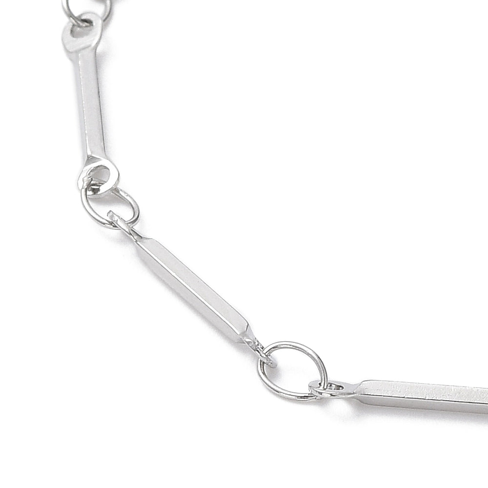 zoomed in section of silver tone bar link chain necklace over white background. 