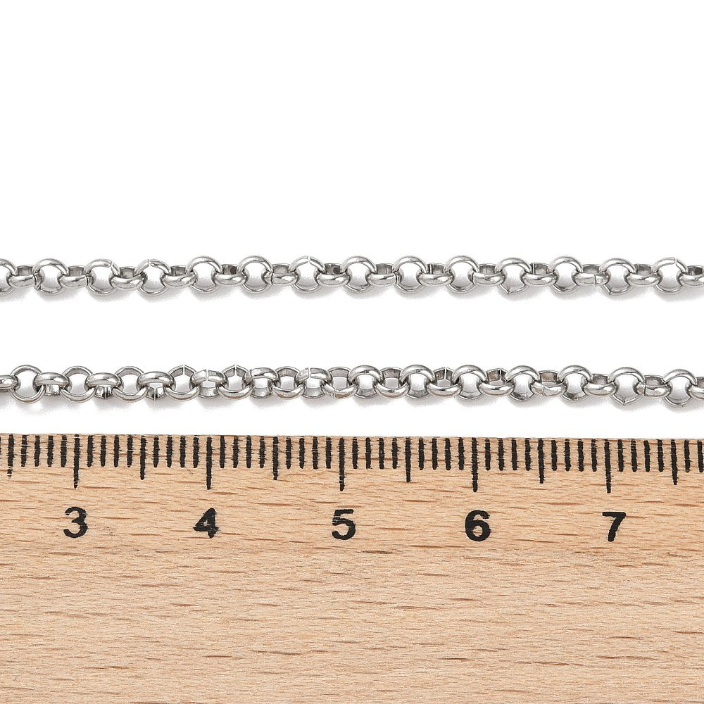 silver tone Rolo chain necklace displayed above wooden ruler on white surface. 