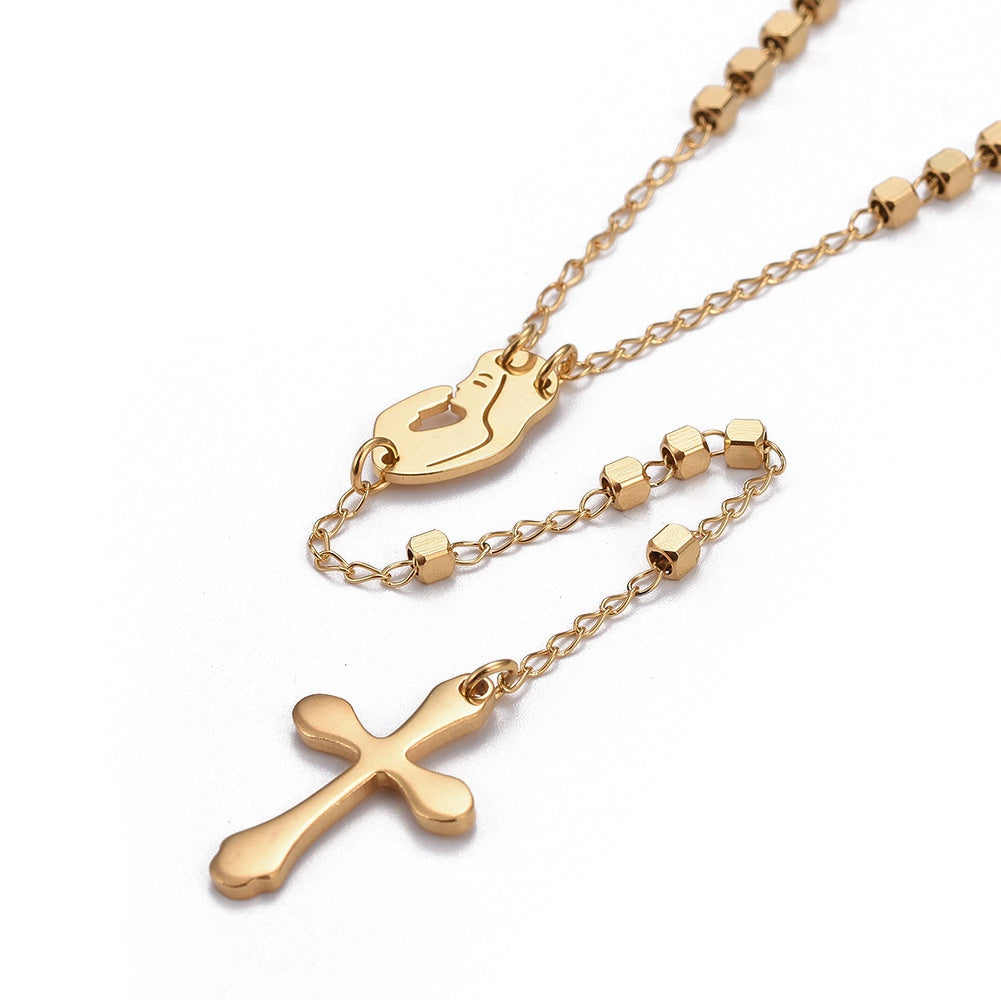 zoomed in section of golden rosary necklace with cube rosary beads a profile of Virgin Mary connector a cross pendant with a lobster claw clasp over white background. 