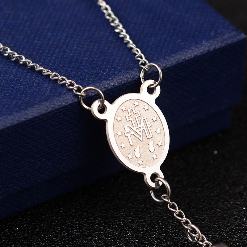 zoomed in back of silver oval medal connector piece draped over blue box onto black surface. 