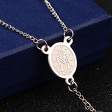 zoomed in back of silver oval medal connector piece draped over blue box onto black surface. 