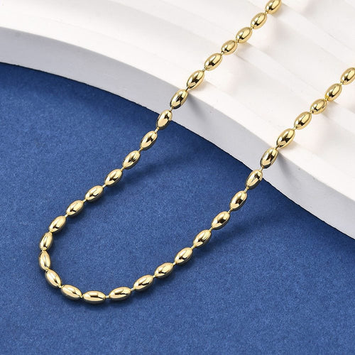 golden oval ball chain draped over white ledge onto blue felt surface. 